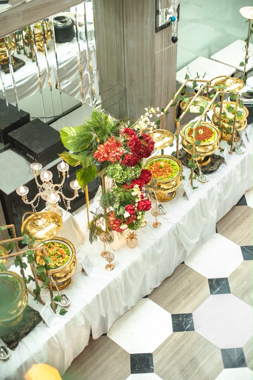 Meja prasmanan Vigee Catering dengan dekorasi bunga dan pemanas emas